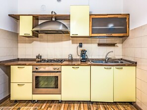 Eine kompakte Küche mit Gasherd, Backofen, Holz Arbeitsplatte und integriertem Mikrowellenherd.