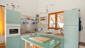 A compact kitchen with a vintage stove, microwave, and a small window. - Bright country house with open kitchen (Saint-Jean-de-Laur)