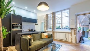 Eine moderne Küche mit Einbauofen, ein Essbereich mit Glastisch und eine gemütliche Sitzecke mit einer Couch.