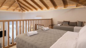 Une chambre avec deux lits, des poutres apparentes en bois au plafond et un balcon doté d’une balustrade en bois.