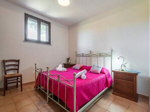 Une chambre à coucher avec un lit en métal, une chaise en bois, une table de chevet et une commode.