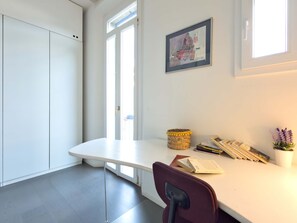 A modern office space with a white desk, a chair, a framed artwork, and a basket on the wall. - Casa Marion Charming Home Near the Center (Bologna)