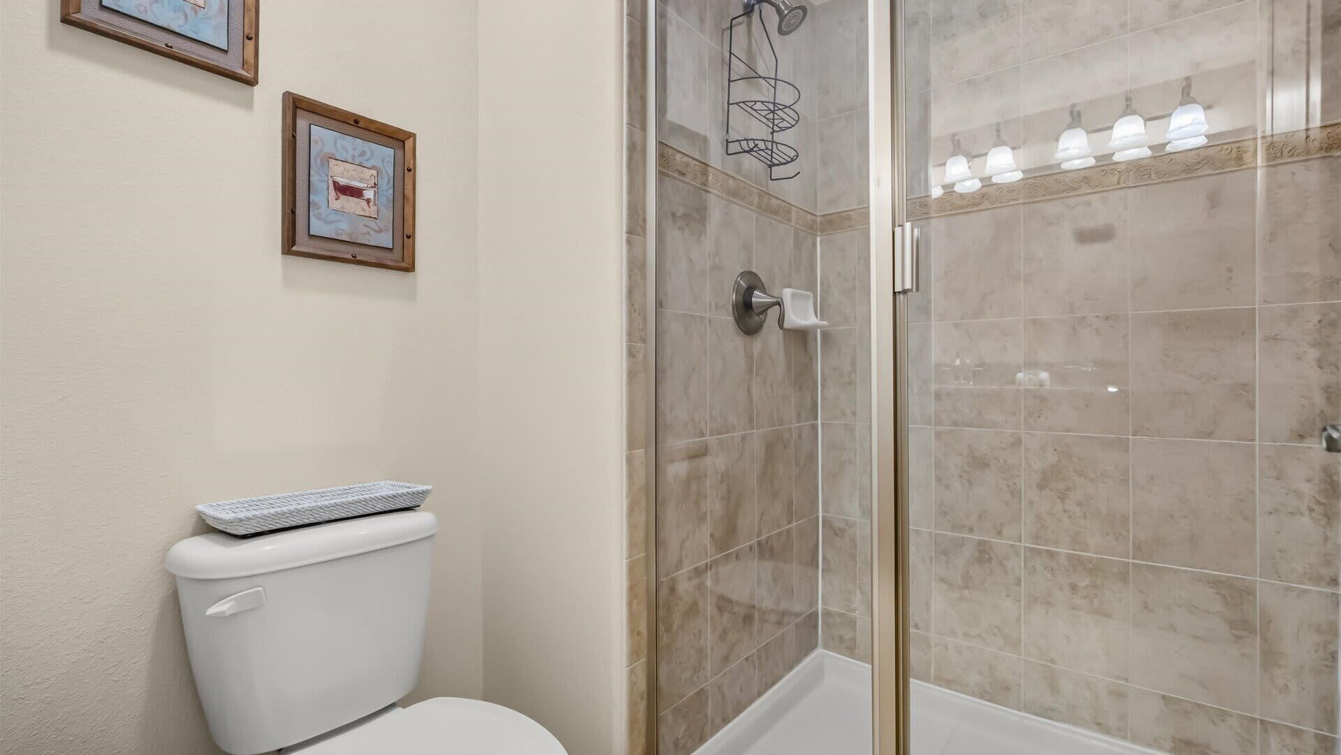 A bathroom with a toilet, a shower with a glass door, and a tiled wall.