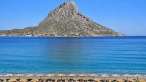 A beach with a rocky hill in the background, umbrellas, and lounge chairs. - Casa Azul Villa - Seafront Getaway in Kalymnos (Kalymnos)