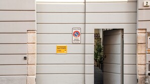 Ein Gebäudeeingang mit einem Verbotsschild für Parkplätze, einem Feuerschutzknopf und einer Tür zu einem überdachten Bereich.