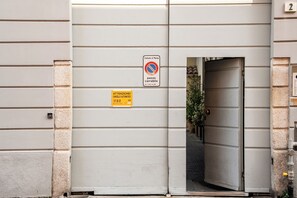 A building entrance with a no parking sign, a fire alarm button, and a door leading to a covered area. - Apartment Monza Station I 15 min Milan City Center (Monza)
