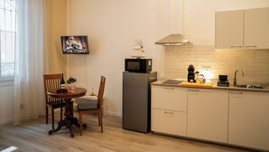 Eine kompakte Küche mit Essbereich, einem Flachbildfernseher, einem Kühlschrank und einer Mikrowelle.