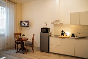 A compact kitchen with a dining area, a flat-screen TV, a refrigerator, and a microwave. - Apartment Monza Station I 15 min Milan City Center (Monza)