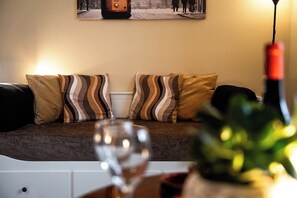 A living room with a sofa, striped cushions, a wine bottle, and a glass. - Monza Station I Apartment: 15 min from downtown Milan (Monza)