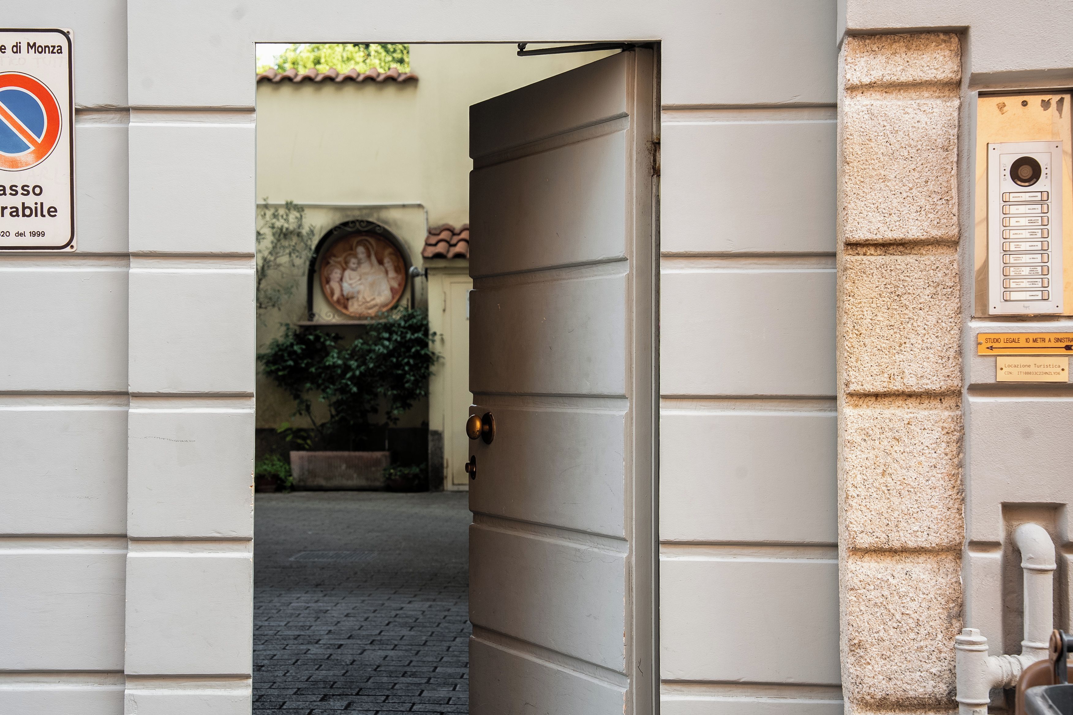 An open doorway leading to a courtyard with a tiled floor and a wall-mounted plaque.
