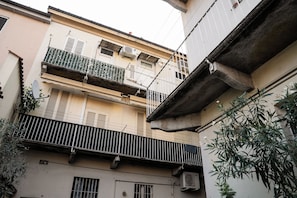 A multi-story building with balconies, air conditioning units, and a concrete overhang. - Monza Station I Apartment: 15 min from downtown Milan (Monza)