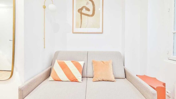 A modern living room with a sofa, two cushions, a framed abstract artwork, and a floor lamp. - Charming Studio - 2P - Eiffel Tower (Paris)
