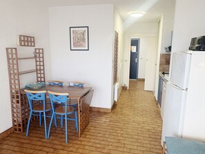 A compact kitchen with a dining area, featuring a wooden table, blue chairs, a refrigerator, and a microwave. - Studio for 4 with Wi-Fi and terrace (Roquebrune-Cap-Martin)