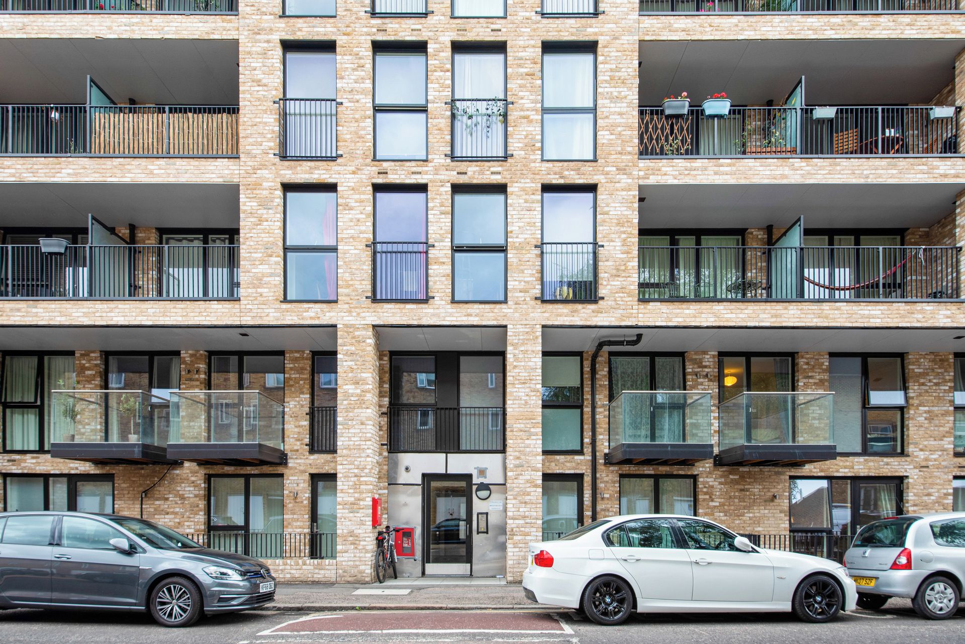 A multi-story residential building with balconies, a garage, and a street view.