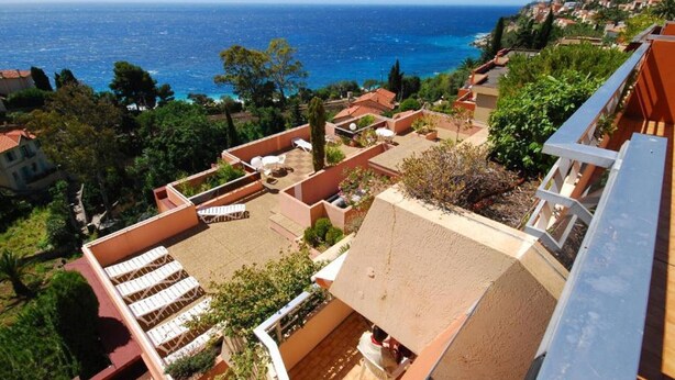 Una terraza en la azotea con mobiliario exterior y vista al mar.