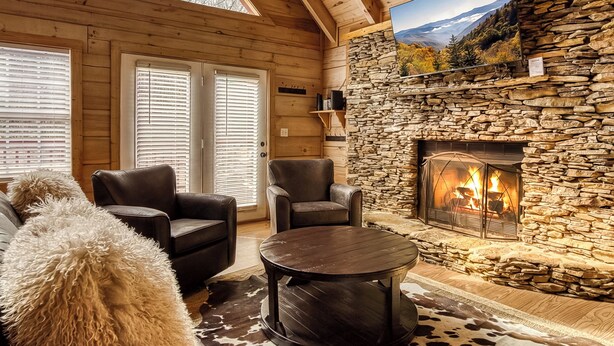 A cozy cabin interior with a stone fireplace, leather chairs, and a large window overlooking a mountainous landscape. - Close to Gatlinburg, 3 bedroom, 2 bath, hot tub, pool table (Gatlinburg)