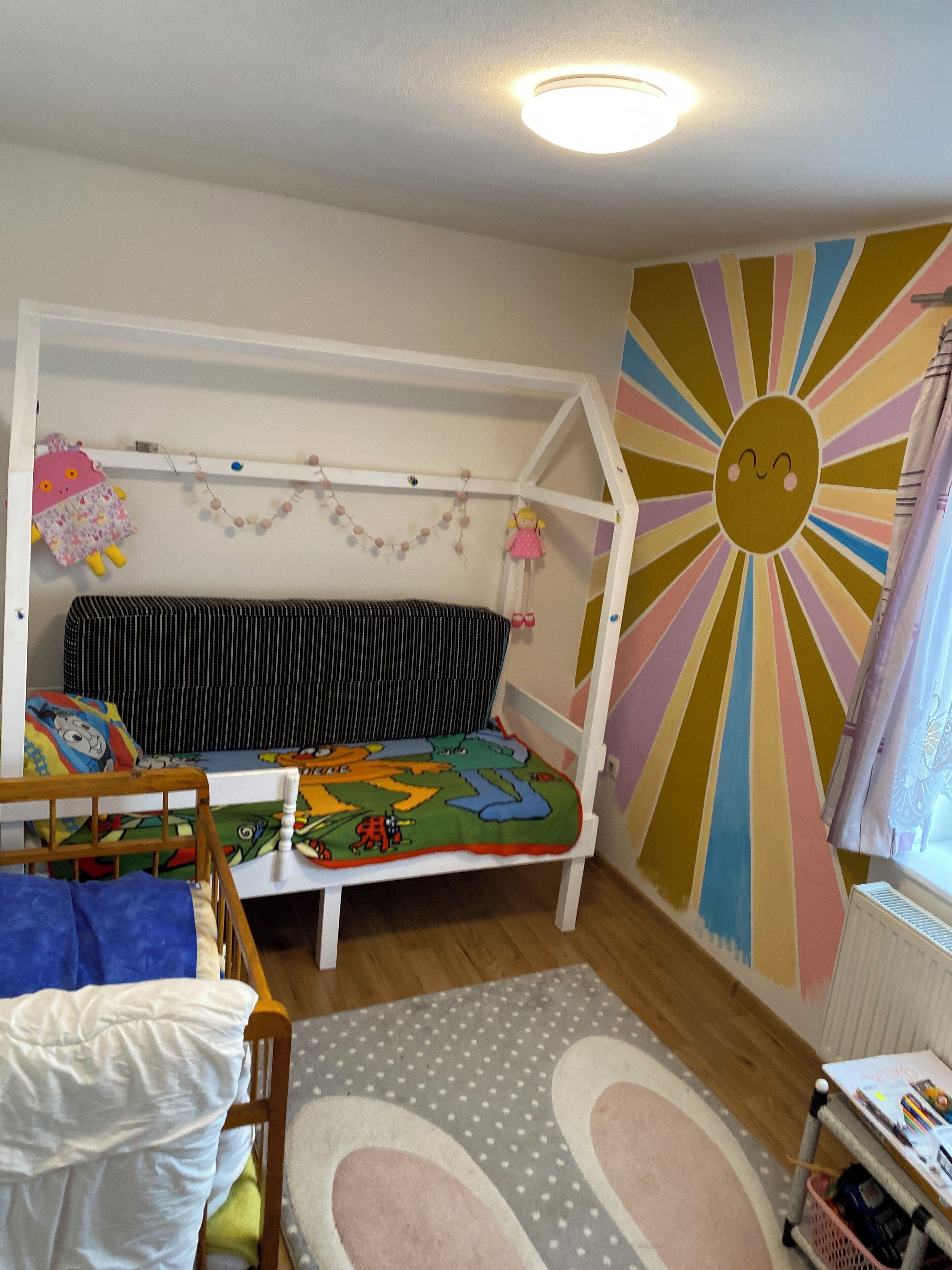 A child's bedroom with a bunk bed, a colorful wall mural, and a window with curtains.