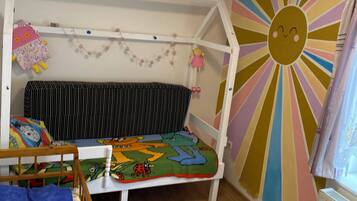 A child's bedroom with a bunk bed, a colorful wall mural, and a window with curtains.
