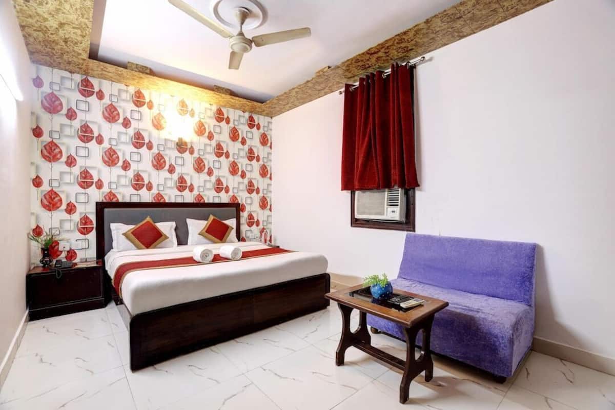 Un dormitorio con cama, sofá, mesa, ventilador de techo y pared con diseño.
