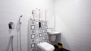 A bathroom with a white toilet, a sink, a shower, and a tiled wall. - Hotel Delhi Darbar-Near Karolbagh Metro (New Delhi)