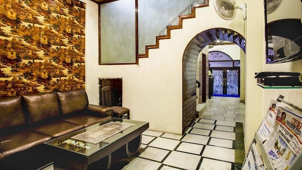 A lobby with a brown leather sofa, a glass coffee table, a patterned wall, a staircase, and a fan. - Hotel Delhi Darbar-Near Karolbagh Metro (New Delhi)