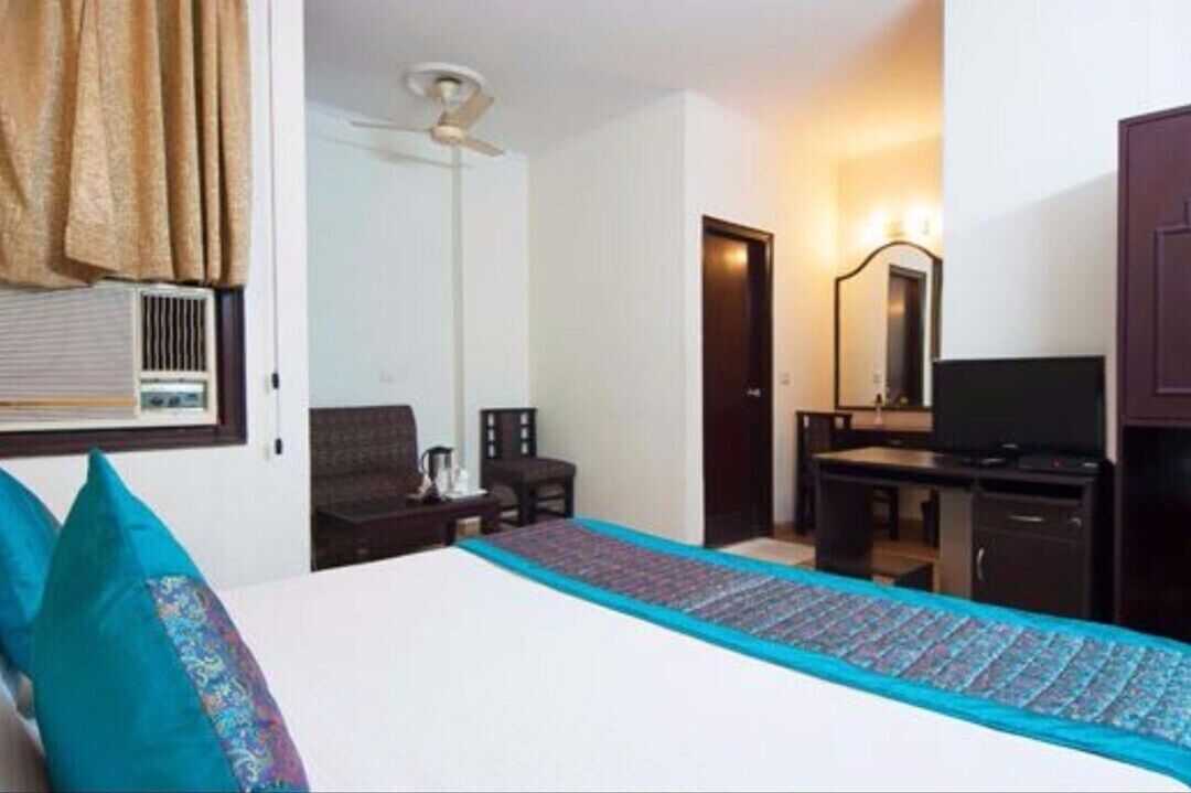 A hotel room with a bed, a desk, a chair, a television, and a ceiling fan.