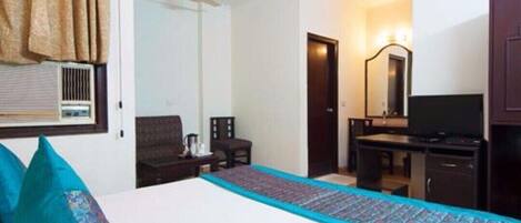 A hotel room with a bed, a desk, a chair, a television, and a ceiling fan.