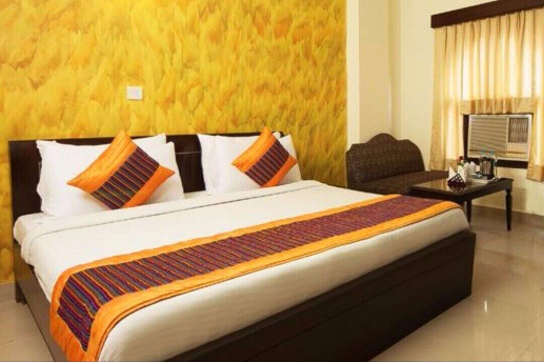 A hotel room with a large bed, a wooden headboard, and a small table with a lamp.