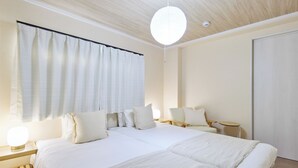 Una habitación de hotel moderna con una cama grande, mesitas de noche, una silla y una pequeña mesa.