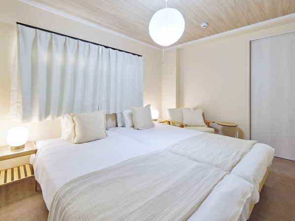 A modern hotel room with a large bed, bedside tables, a chair, and a small table.