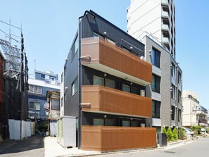 A modern multi-story building with balconies, large windows, and a mix of brick and metal exterior.