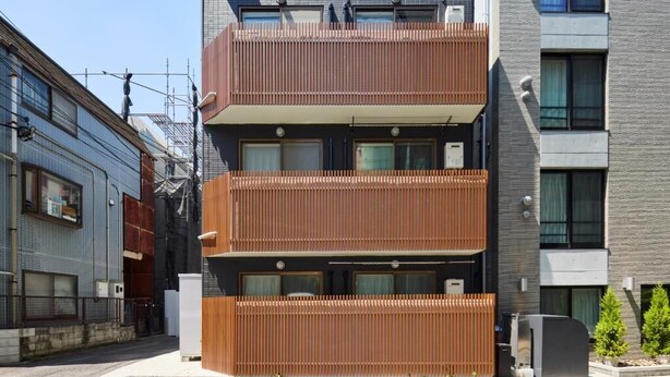Un edificio residencial de varios pisos con diseño moderno, que presenta balcones y una combinación de materiales de ladrillo y metal.