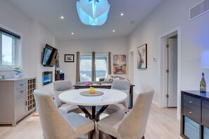 Uma sala de jantar moderna com uma mesa redonda, cadeiras, uma TV de tela plana e obras de arte nas paredes.