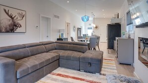 Una sala de estar moderna con un sofá seccional, un comedor y una cocina.