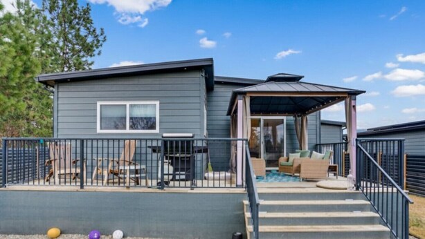 Una casa moderna con un porche cubierto, mobiliario exterior y una piscina pequeña.