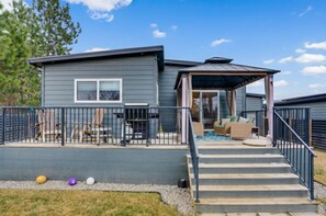 A modern house with a covered patio, outdoor seating, and a small pool. - Modern 2 Bedroom Rancher in Beautiful Lake Country (Kelowna)