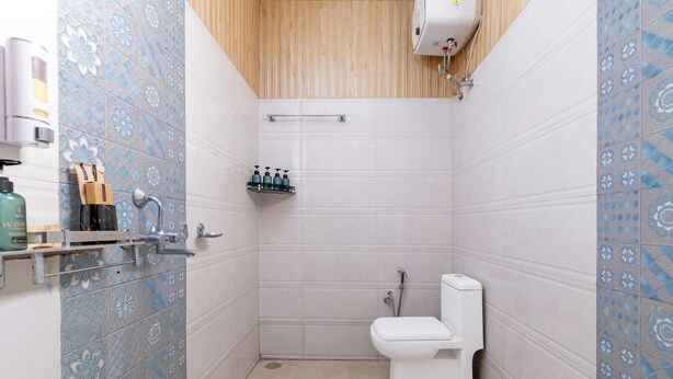 Un baño pequeño con inodoro, estante de artículos de aseo y zona de ducha.