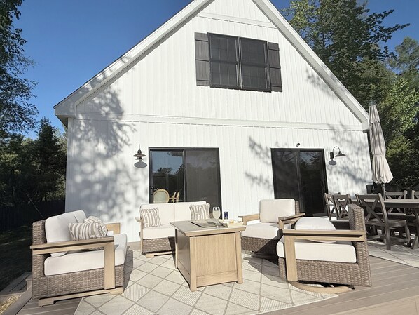 A white building with a large deck, outdoor furniture, and two large windows. - Driftwood on Torch River (Rapid City)