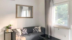 A modern living room with a grey sofa, a glass coffee table, and a large mirror on the wall. - Amazing home in Cizici (Cizici)