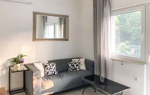Ein modernes Wohnzimmer mit einem grauen Sofa, einem Glastisch und einem großen Spiegel an der Wand.