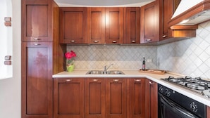 A kitchen with wooden cabinets, a stainless steel sink, and a gas stove. - Home Thoughtfully Designed for the Comfort (Siniscola)