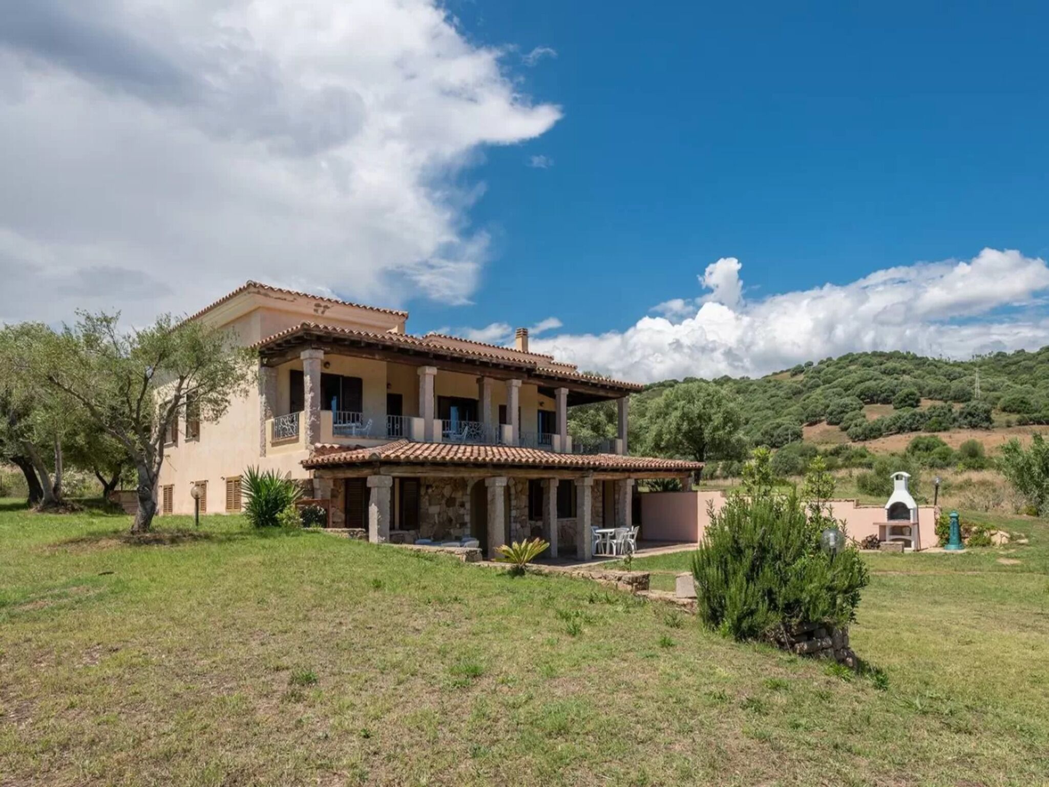 A two-story house with a tiled roof, a balcony, and a small patio area.