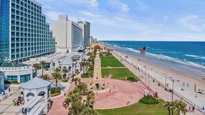 A coastal hotel with a beach promenade, a central fountain, and a clock tower. - Ocean Oasis - Ocean View At Symphony Beach Club and King Bed (Ormond Beach)