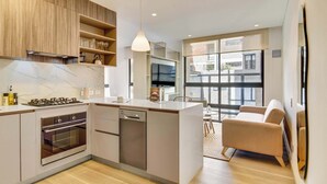 A modern kitchen with built-in appliances, a dining area with a sofa, and large windows offering a view of the city. - w Stylish Radiant Loft in Chapinero (Bogotá)
