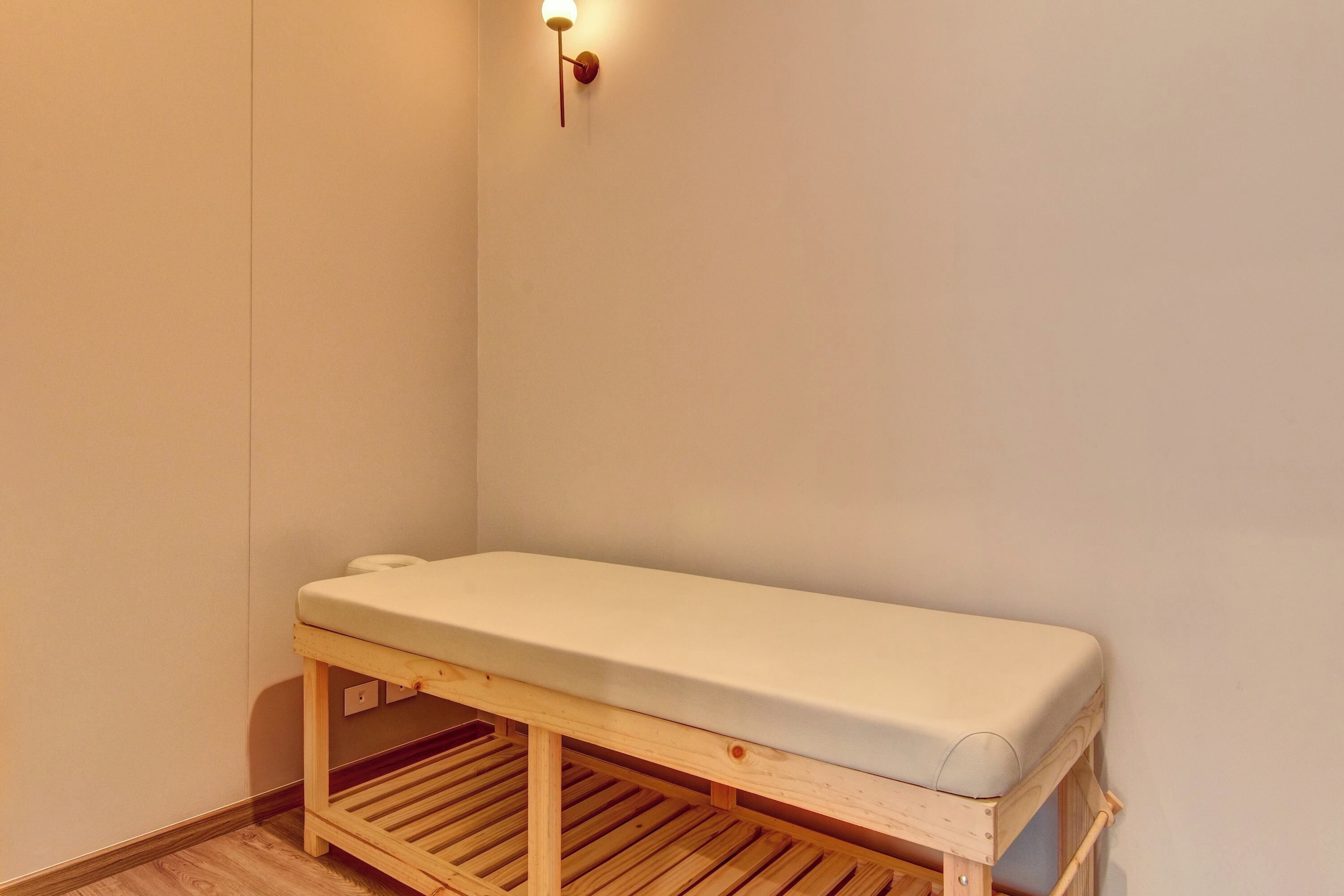 Un petit banc en bois avec un coussin blanc, placé dans un coin de la pièce.