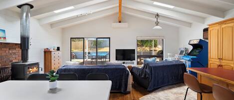 Amplia sala de estar con techo alto, chimenea, televisor y mesa de comedor.