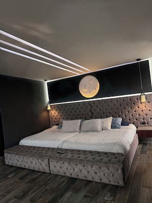Un dormitorio moderno con un cabecero capitonado, una cama grande con colcha acolchada y un adorno circular en la pared.