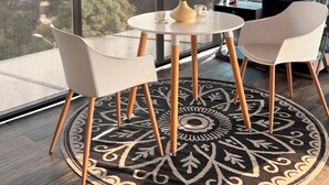 A modern room with a large window, a round table with chairs, a decorative vase, and a patterned rug. - MOVISTAR ARENA PENTHOUSE (Bogotá, D.C.)