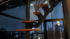 A modern interior with a glass staircase leading to a balcony. - MOVISTAR ARENA PENTHOUSE (Bogotá, D.C.)