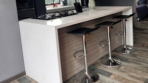 A modern kitchen with a central island, bar stools, and a built-in stove. - MOVISTAR ARENA PENTHOUSE (Bogotá, D.C.)